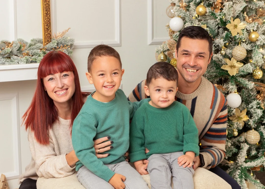 Familia con dos niños en sesión de Navidad junto al árbol en Guadarrama