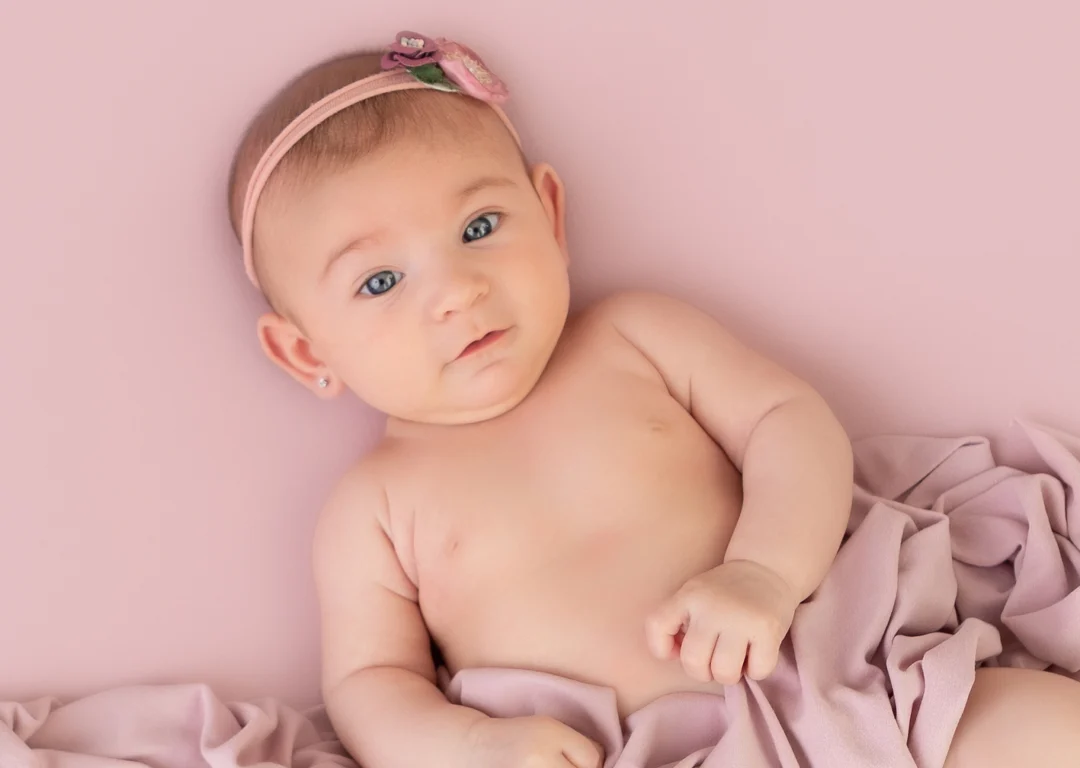Fotografía de bebé de 4 meses boca arriba sonriendo durante su sesión de fotos en estudio en Madrid.
