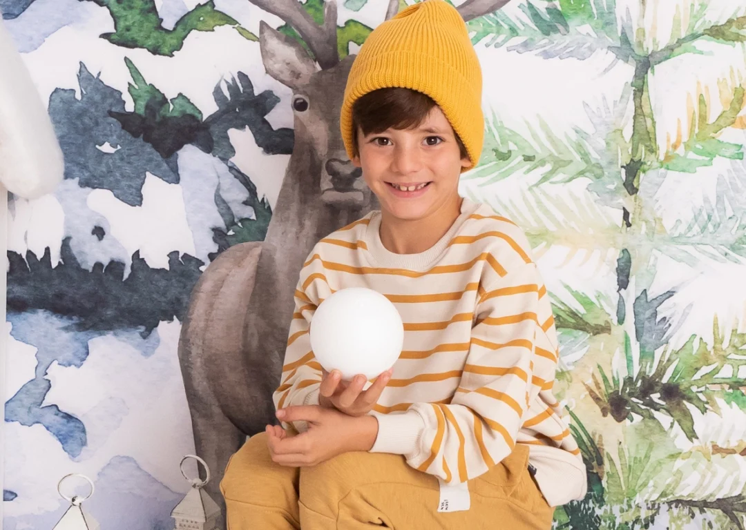 Niño con bola de nieve en sesión navideña con decorado nórdico en Guadarrama