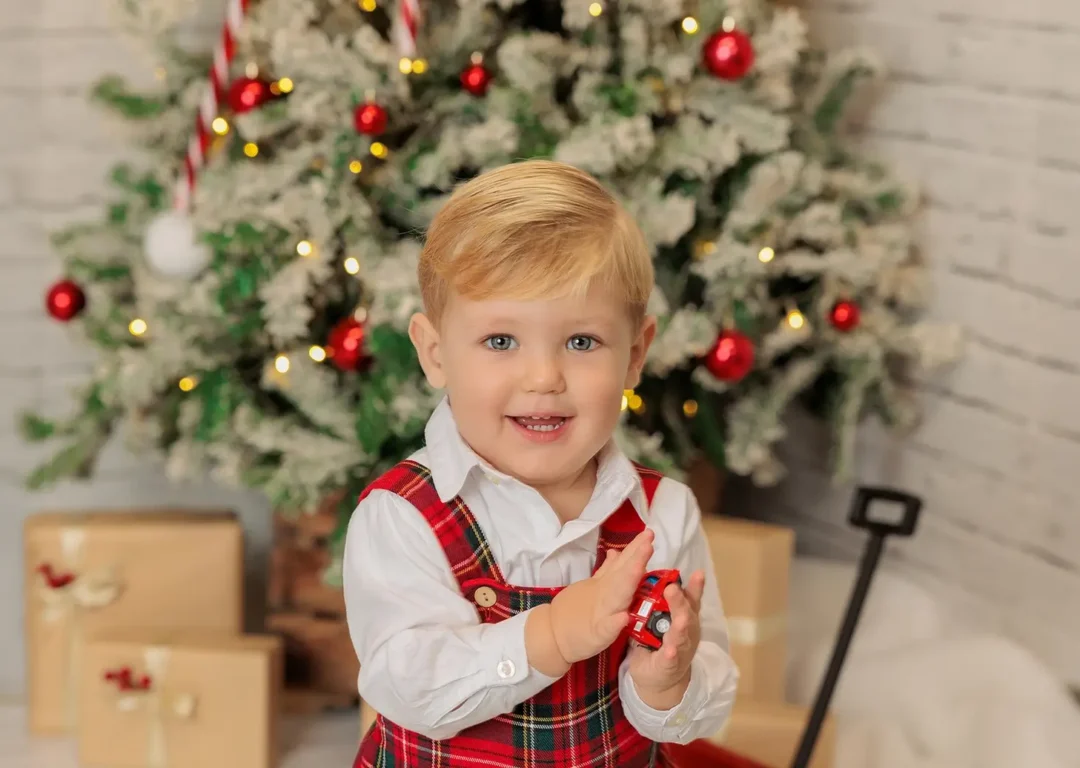 Niño en sesión de fotos de Navidad junto al árbol en estudio en Guadarrama, Madrid