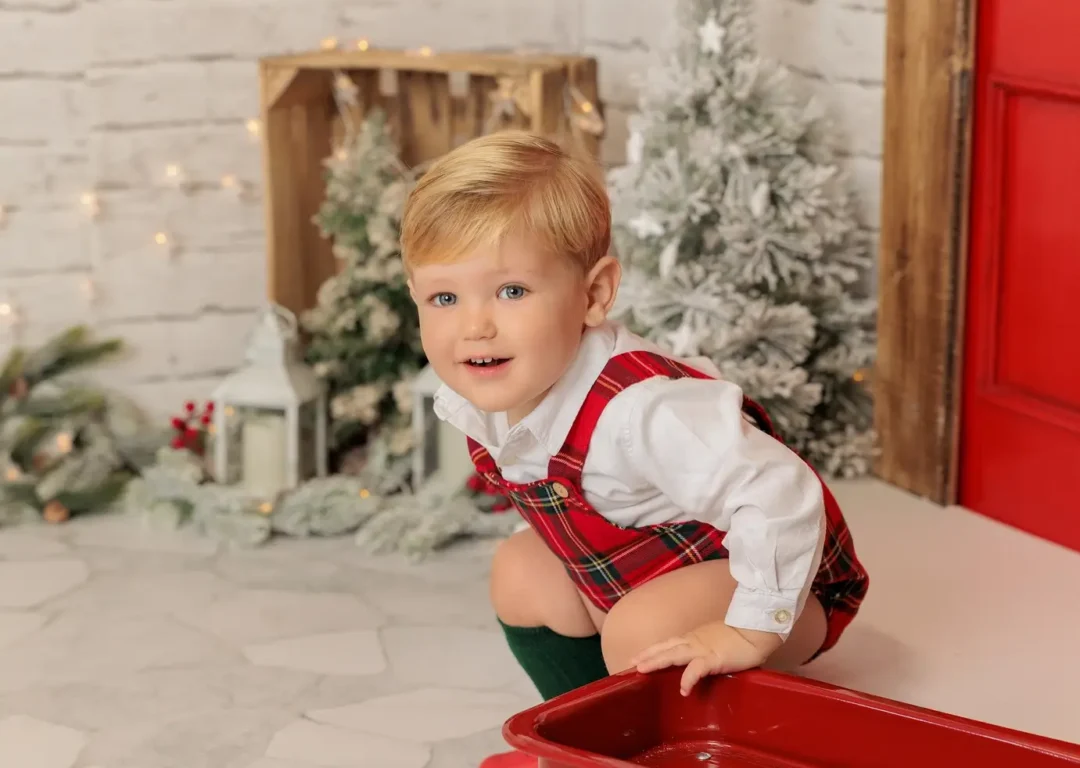 Niño con vestuario navideño junto a chimenea decorada en estudio en Guadarrama